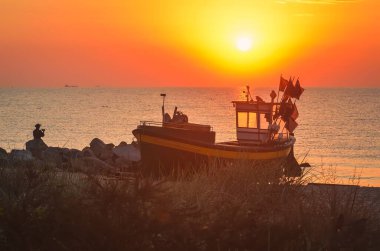 Deniz kenarındaki renkli sabah manzarası. Sahilde güneşin doğduğu güzel bir tekne. Fotoğraf: Gdynia, Polonya.