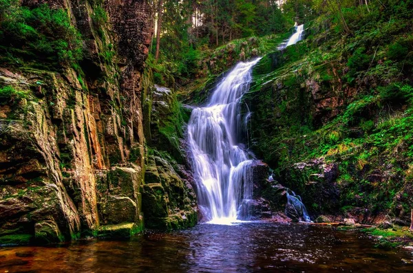 Charming waterfall in the mountains among rocks and green plants. Famous Kamienczyk waterfall in the Karkonosze National Park, Poland.