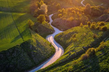 Yeşil tepelerin arasındaki güzel bahar manzarası. Yeşil doğa arasındaki büyüleyici dolambaçlı yol. Fotoğraf: Grodzisko - Stradow, Polonya.