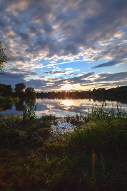 Kırsal bölgedeki göl kenarındaki güzel renkli manzara. Polonya, Kielce yakınlarındaki Mojcza gölünde gün batımı.