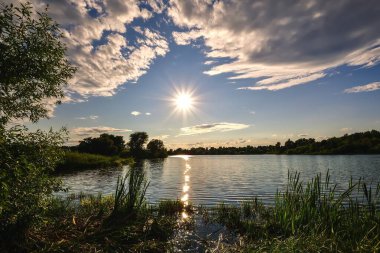 Kırsal bölgedeki göl kenarındaki güzel renkli manzara. Polonya, Kielce yakınlarındaki Mojcza gölünde gün batımı.