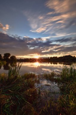 Kırsal bölgedeki göl kenarındaki güzel renkli manzara. Polonya, Kielce yakınlarındaki Mojcza gölünde gün batımı.