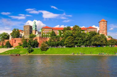 Krakow, Polonya - 16 Ağustos 2014: Krakow'daki Wawel Kraliyet Kalesi. Güneşli yaz gününde arka planda Wawel Royal Castle ile Vistula nehri üzerinde Turist ve tekne, Polonya.