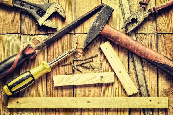 Renovation tools in vintage style. Hammer, flat file, pliers, screwdriver, monkey wrench, screws, boards and blade on natural wooden background.