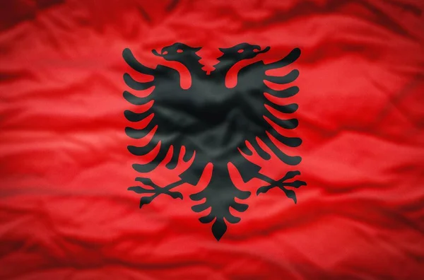 Albanian flag on a fabric wavy background. Wavy flag of Albania fills the frame.