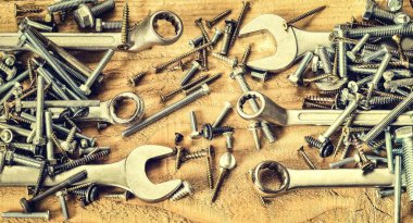 Vidalar ve anahtarlar. Doğal ahşap arka planda bir yığın cıvatalar, fındıklar, vidalar, anahtarlar ve halka yayıcıları.
