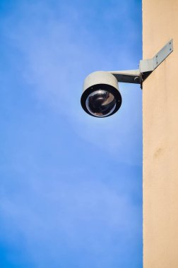 Apartman dairesinin duvarında belediye gözetimi var. Mavi gökyüzü arkaplanına karşı binadaki güvenlik kamerası.