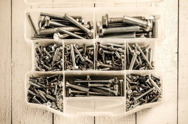 Gümüş ve altın renkli vidalar. Tahta beyaz bir masa üzerinde vida ve cıvatalar ile alet kutusu.