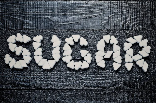 白不健康な砂糖との概念 黒い木の板に砂糖キューブの碑文 — ストック写真