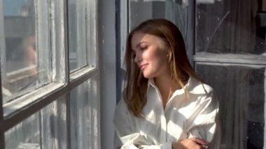 Güneşli bir günde pencerenin yanında poz veren rahat bir model.