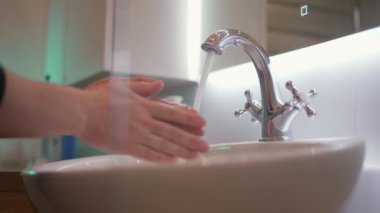 Yetişkin bir adam banyoda sabunla ellerini yıkıyor. Hijyen ve koronavirüs önleme kavramı