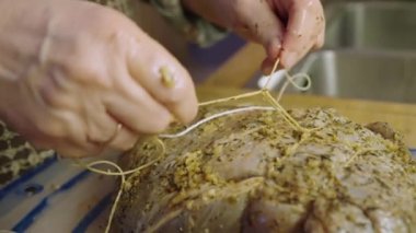 Ev hanımı kızartılması için baharatlı çiğ dana eti bağlıyor.