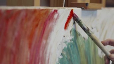 Ressam, bir stüdyoda tuvale yağlı boya bir tablo çiziyor, ressam da yakından çalışıyor.