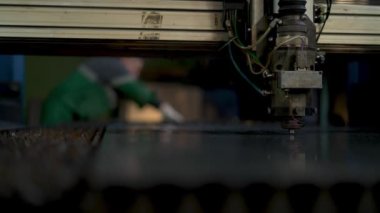 CNC lazer makinesinde çalışan teknisyen metal levha kesiyor