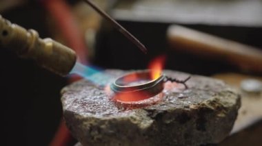 Craftsman soldering the metal tip of the scabbard in the workshop