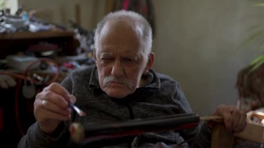 Elderly male master works in his workshop restoring japanese sword sheath