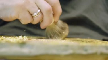 Ressam, tuvaldeki yağlı boya resme altın uygular.