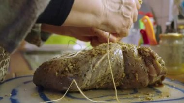 Ev hanımı kızartılması için marine edilmiş çiğ dana etini bağlıyor.