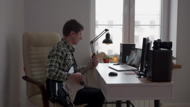 Młody Człowiek Gra Gitarze Elektrycznej Siedząc Biurkiem Pokoju Dzień — Wideo stockowe