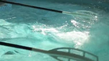 Antrenman sırasında havuzda kürek çeken bir spor simülatörünün kürekleri