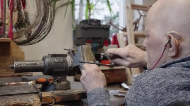 Tekerlekli sandalyedeki kıdemli yaşlı kuyumcu bir atölyede çalışıyor.