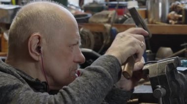 Tekerlekli sandalyedeki kıdemli yaşlı kuyumcu bir atölyede çalışıyor.