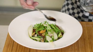 Şef deniz ürünleri, armut ve kurutulmuş domates salatası servis ediyor.