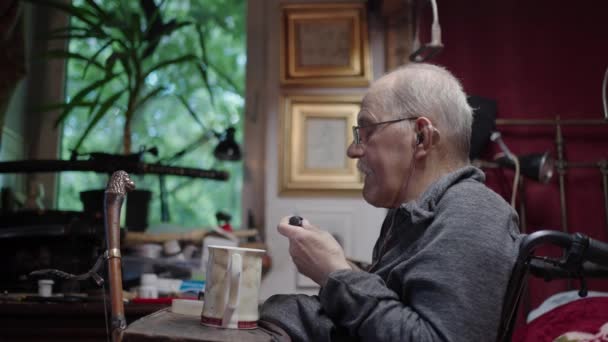 坐在轮椅上的老人在卧室的床边吃药 — 图库视频影像