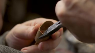 Tekerlekli sandalyedeki yaşlı usta kuyumcu bir atölyede çalışıyor.