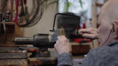 Tekerlekli sandalyedeki kıdemli yaşlı kuyumcu bir atölyede çalışıyor.