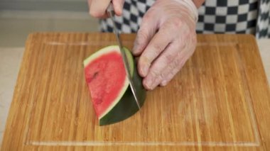 Şef olgun karpuz dilimlerini tahta kesme tahtasıyla kesiyor.