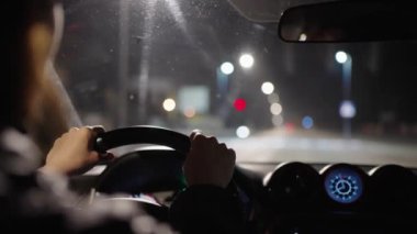 Bir kadın büyük bir şehrin banliyö bölgesinde gece araba kullanıyor.