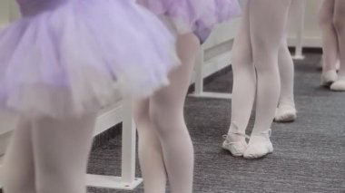 Küçük kızlar koreografi eğitimi sırasında bale egzersizleri yaparlar.