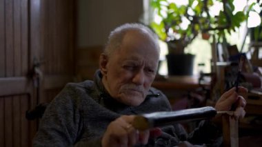 Elderly male master works in his workshop restoring japanese sword sheath