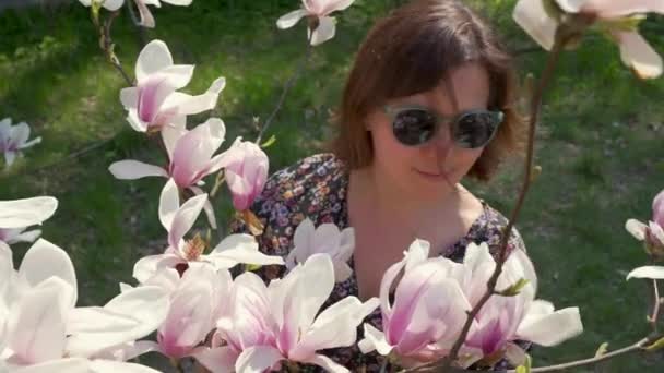Mulher Feliz Óculos Sol Apreciando Natureza Tocando Flores Magnólia Florescendo — Vídeo de Stock