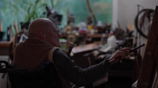 Senior Kunstenaar Een Rolstoel Schildert Een Olieverf Doek Een Atelier — Stockvideo