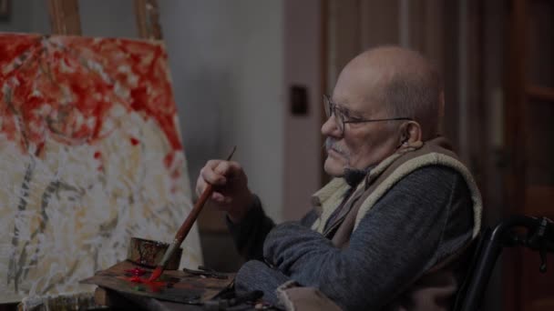 轮椅上的资深画家在工作室的画布上画了一幅油画 画家在工作 — 图库视频影像