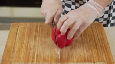 Şef kırmızı biberi tahta kesme tahtasına dilimliyor.