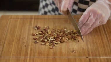 Kesme tahtasının üzerinde büyük bir mutfak bıçağıyla badem öğütüyorsun.