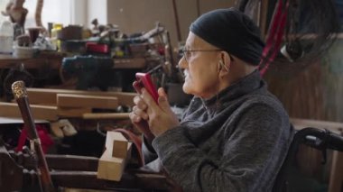 Tekerlekli sandalyede oturan yaşlı adam akıllı telefondan sosyal medyada kayıyor.