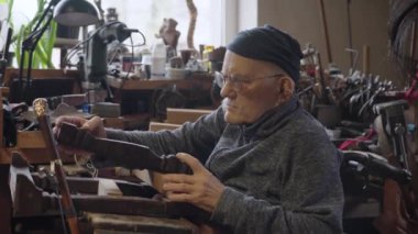 Tekerlekli sandalyedeki yaşlı erkek usta atölyesinde mobilyaları restore ediyor.