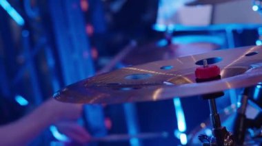 Erkek müzisyen parti sırasında renkli sahne ışıkları altında davul çalıyor.