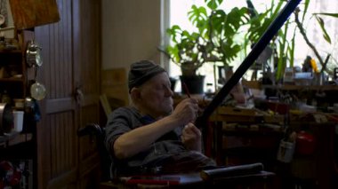 Yaşlı erkek usta atölyesinde Japon kılıç kılıfını restore ediyor.