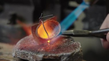 Craftsman soldering the metal tip of the scabbard in the workshop