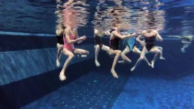 Senkronize yüzme takımı yüzme havuzunda, su altında antrenman yapıyor.
