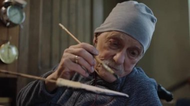 Yaşlı erkek üstat atölyesinde çalışıyor. Japon Deba bıçağını kılıfıyla restore ediyor.