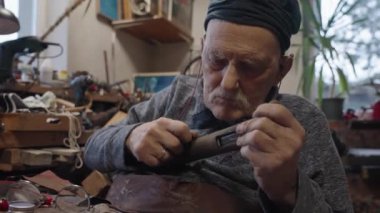 Elderly male master works in his workshop restoring japanese sword sheath