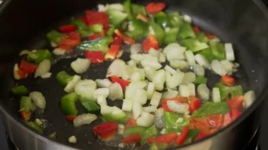 Şef sebze omleti pişirirken tavada doğranmış sebze kızartıyor.