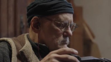Tekerlekli sandalyedeki yaşlı erkek usta atölyesinde mobilyaları restore ediyor.
