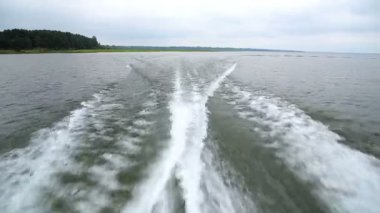 Sürat teknesi tarafından Göl kıyısındaki bir bulutlu yaz gününde seyir ederken arkasında dalgaların görünümü